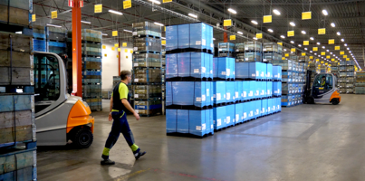 A man walking through a warehouse filled with boxes.