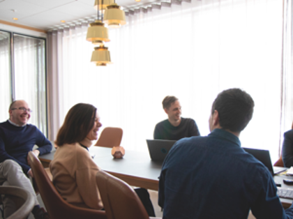 A group of people sitting around a table with laptops.
