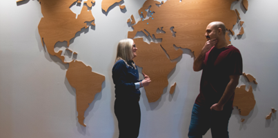 Two people standing in front of a big world map