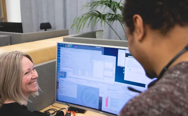 A woman sitting in front of a computer monitor.