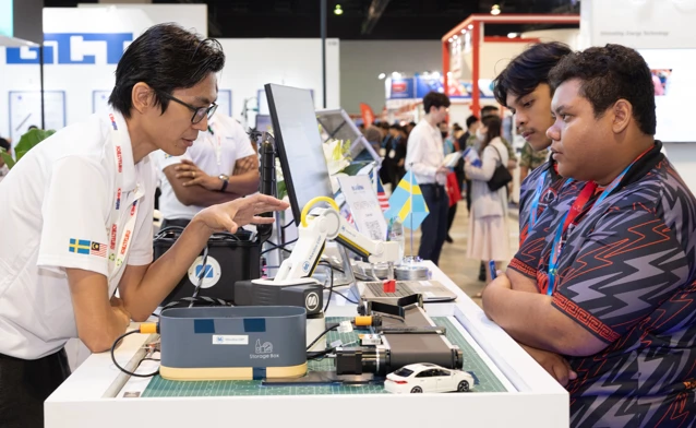 Monitor ERP representatives speaking with manufacturing professionals at an industry exhibition