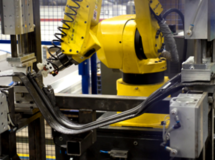 En robot arbetar med en maskindel i produktion. 