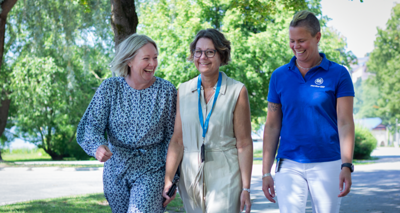 Tre medarbetare går en promenad utomhus. De skrattar.