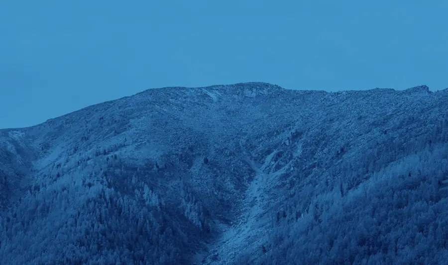 A mountain covered in snow under a blue sky.
