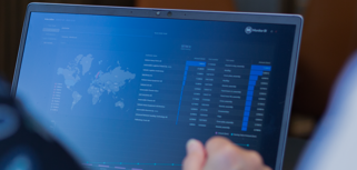 A person sitting in front of a laptop computer with Monitor BI (business intelligence) dashboards. 