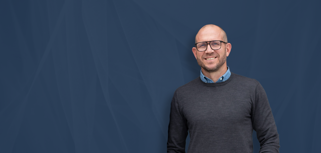 Johan Holmsten, global sales manager at Monitor ERP, standing infront of a blue background