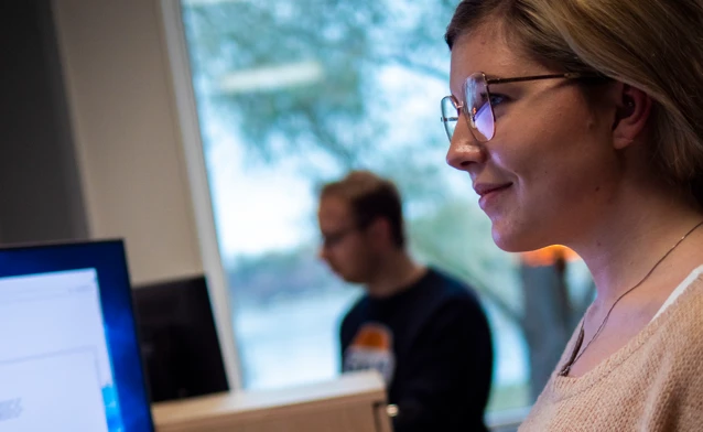 En kvinna med glasögon tittar på en datorskärm.