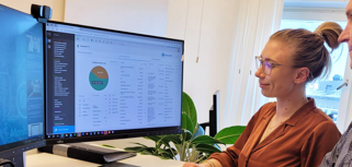 Två personer står framför en dator, där den ena demonstrerar och förklarar hur affärssystemet Monitor ERP fungerar för den andra.