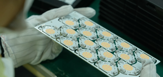 A person in white gloves holding a box of pills.