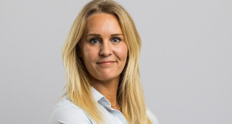 Jenny Tiedman, ansvarig för redovisning och logistik på Skotte står bakom en grå bakgrund.
