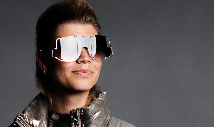 A woman wearing a shiny jacket and sunglasses.