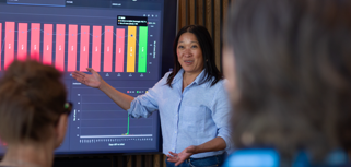 A woman at Monitor ERP giving a presentation to a group of people about Monitor BI (business intelligence)