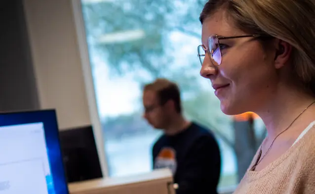 A woman wearing glasses looking at a computer screen.