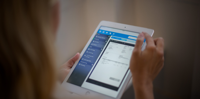 A woman is holding a tablet displaying a digital invoice. 