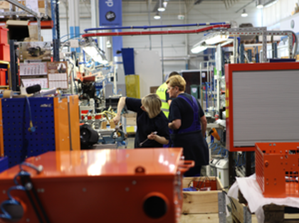 En grupp människor står samlade i en fabrik.