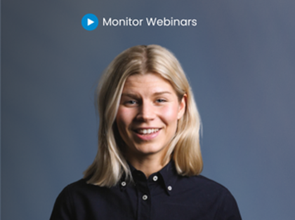 En kvinna tittar in i kameran. Hon står framför en blå/grå bakgrund med texten "Monitor Webinars". 