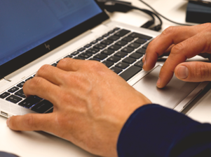Person entering information on a laptop to transfer customer orders between companies