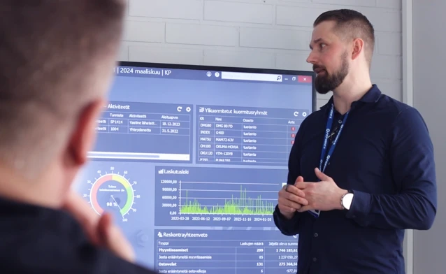 En man står framför en stor skärm som visar affärssystemet Monitor ERP.