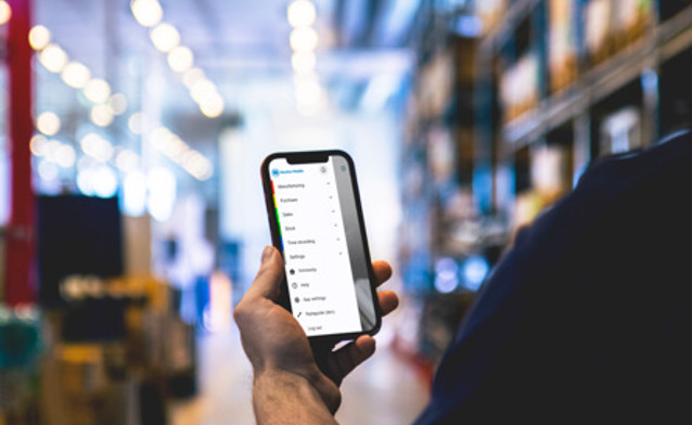 Warehouse worker using Monitor Mobile on a smartphone to manage stock and warehouse operations.