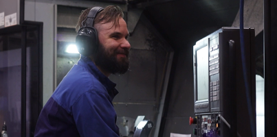 A man in a blue shirt and headphones working on a machine.
